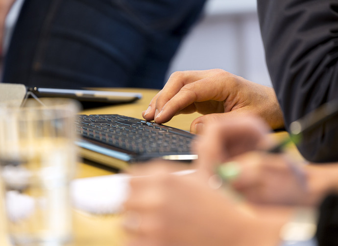 En grupp människor som skymtas runt vid ett bord och en person skriver på ett tangentbord.