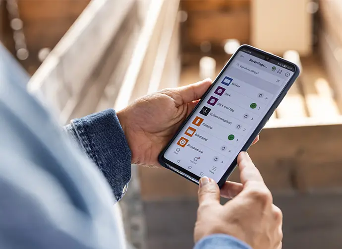 Kvinna håller i en mobiltelefon med appen Avfall & Vatten aktiv