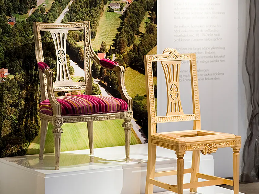 Lindomestolar. En stol med vacker klädsel och en återskapad stol som är trären utan färdig sits.