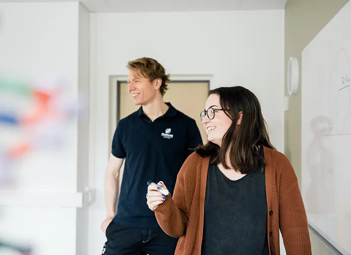 Elev och lärare samarbetar vid tavla och diskuterar uppgifter i klassrummet.