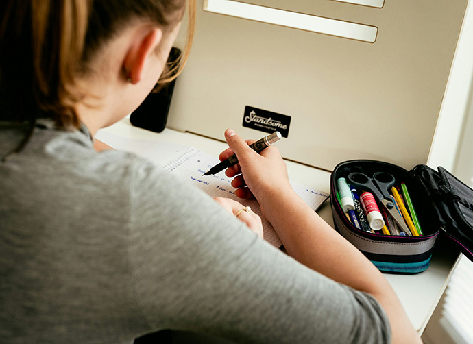 Person skriver anteckningar vid studieplats.