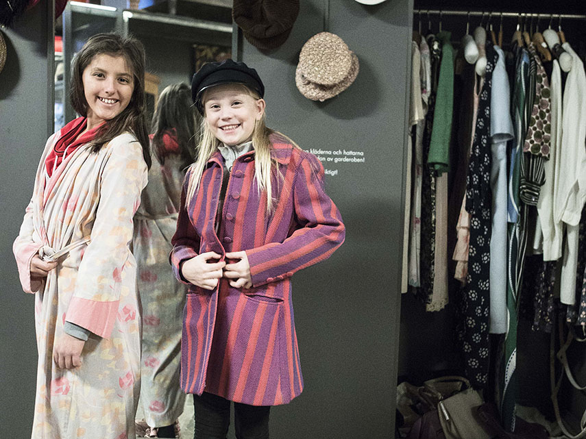 Två tjejer provar kläder i Mölndals stadsmuseums Öppna magasin.