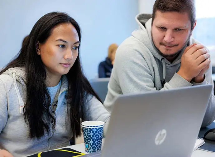 Två elever tittar på en datorskärm i ett klassrum.