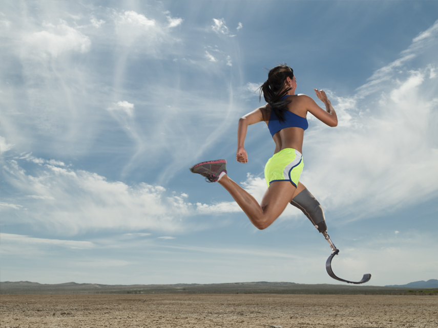 En kvinnlig löpare med benprotes springer i öknen