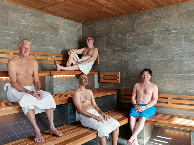 Fyra män sitter och badar bastu i Åbybadet. 