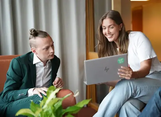 En kvinna visar något på en laptop för för en man.