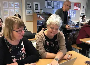 pedagoger sitter i ett klassrum och arbetar i par framför datorer