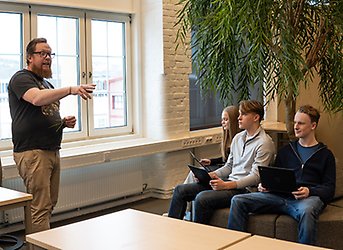 Lärare undervisar elevgrupp med laptops.