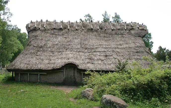 Ett hus som ska likna ett hus från bronsåldern. Huset har ett vasstak och byggt i trä.