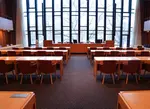 Mölndals fullmäktigesal, ett stort rum med flera rader av bord och stolar framför ett stort väggtäckande fönsterparti .